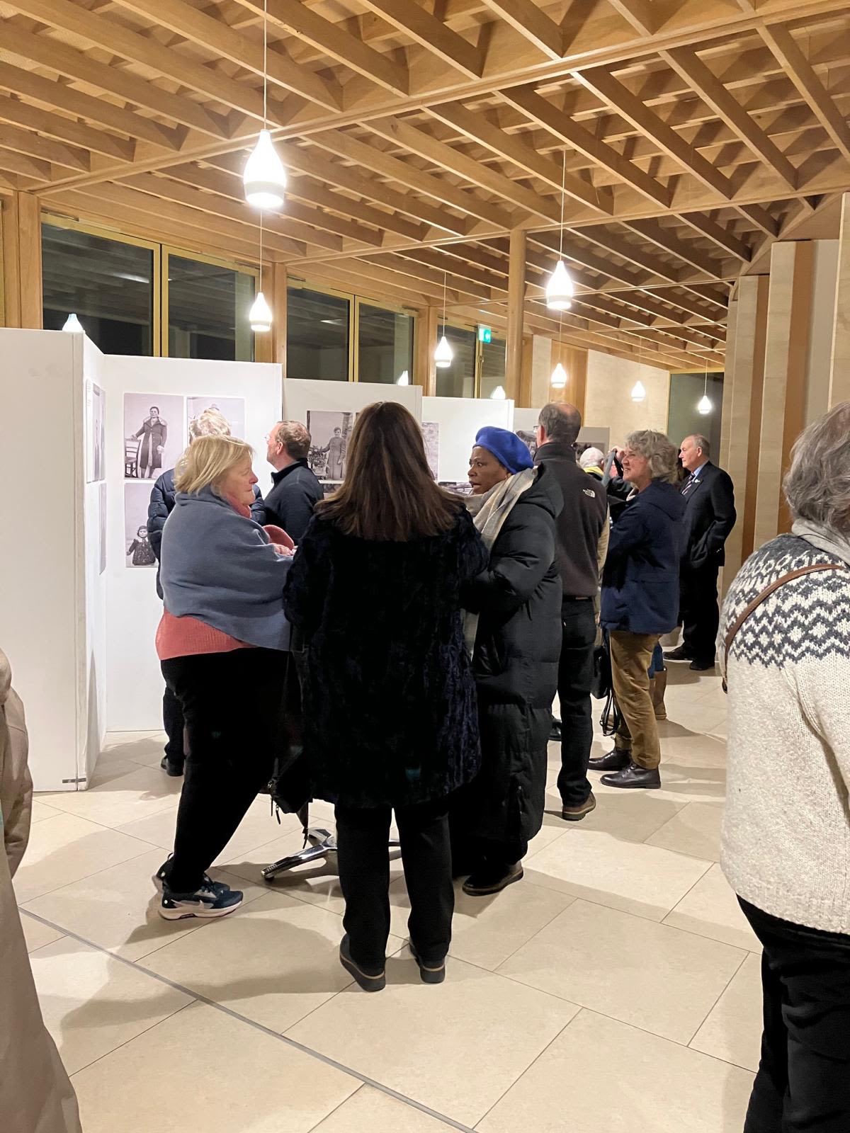 People touring an exhibition of impressive photos of contadini in a gallery setting